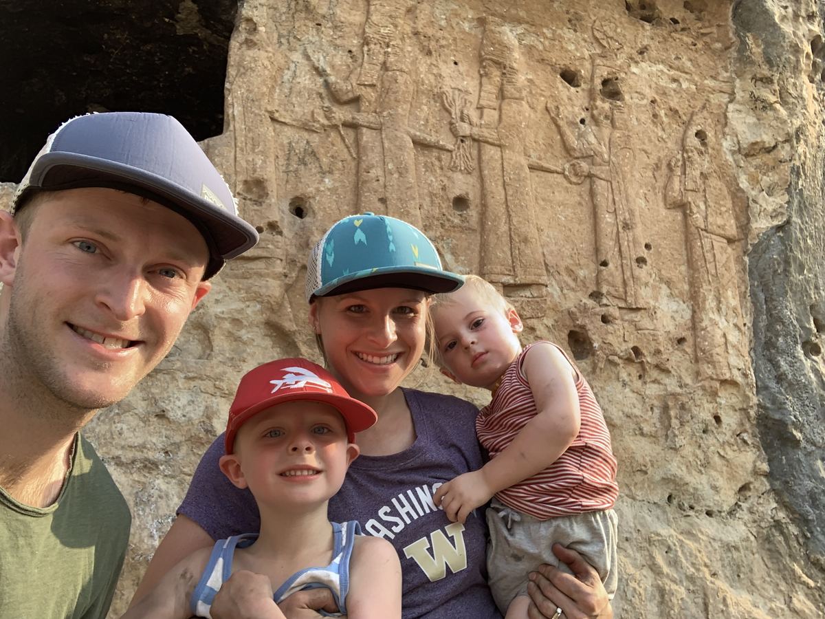 Jamie Watt, his wife and two of their sons in front of an ancient rock relief of a procession of gods